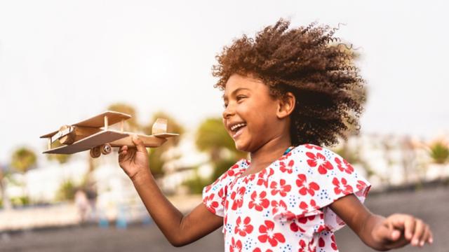 Young girl plays outside with a toy airplane